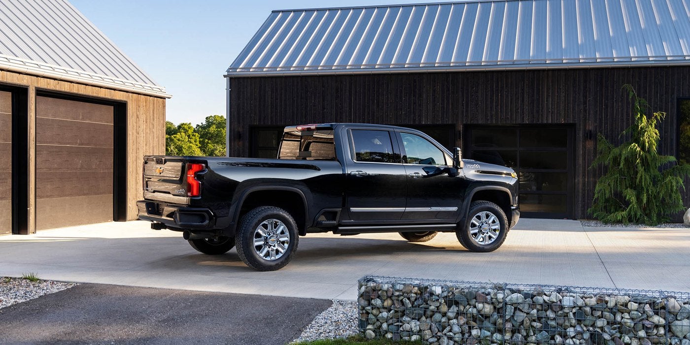 Black Silverado HD crew cab parked on a driveway beside a modern garage