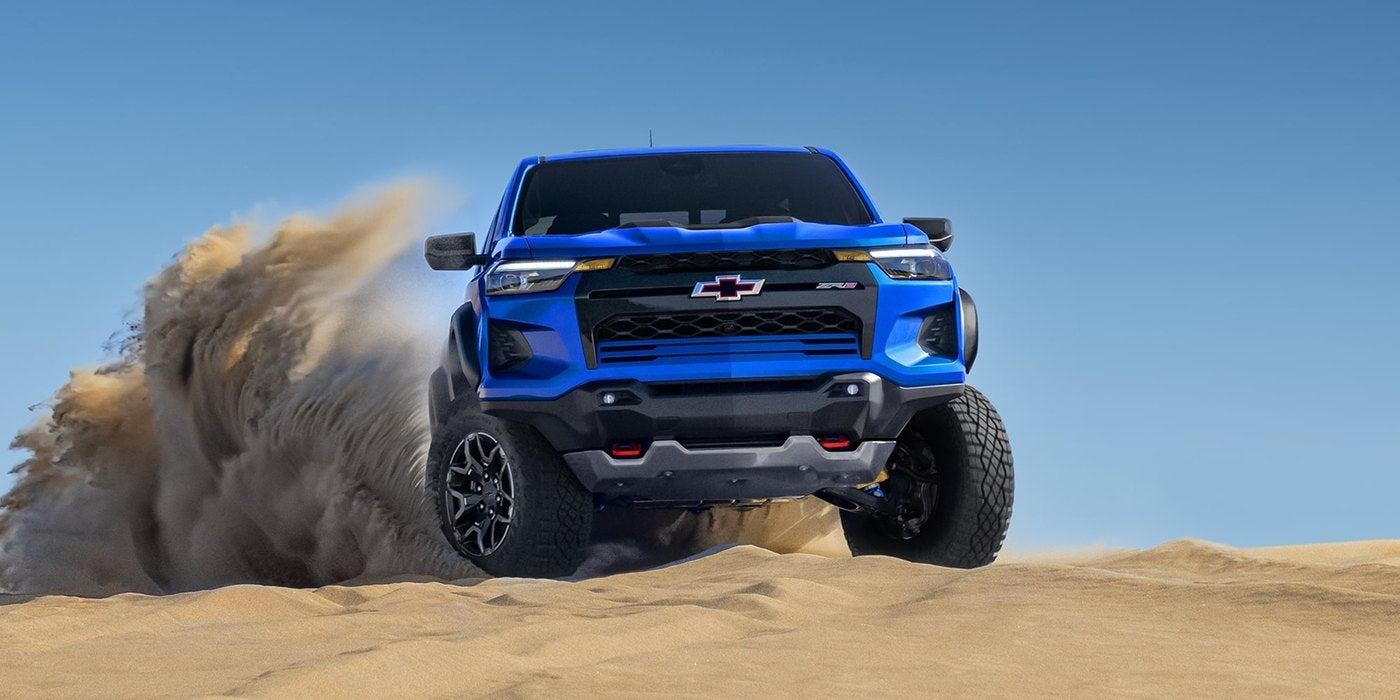 Blue Chevrolet Colorado ZR2 driving through sand with a dust cloud behind it