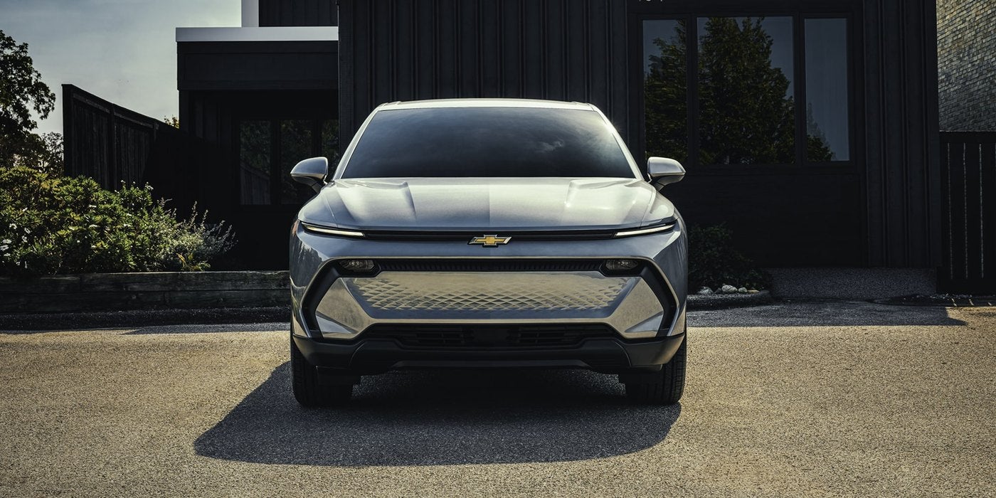 Gray Chevrolet electric SUV parked head on in front of a dark modern building