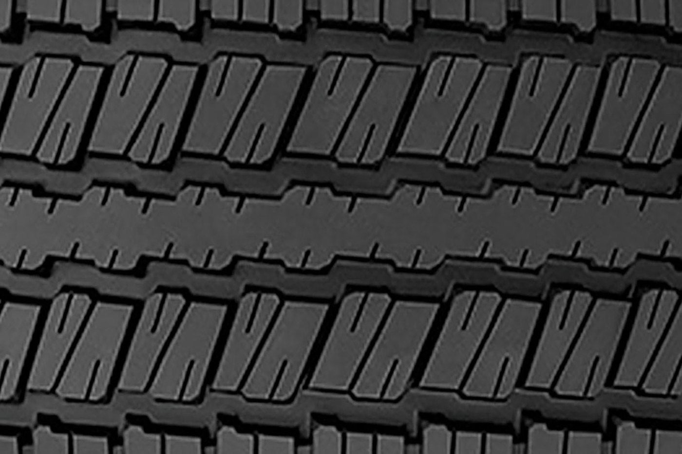 Close view of a deep truck tire tread with wide blocks and grooves